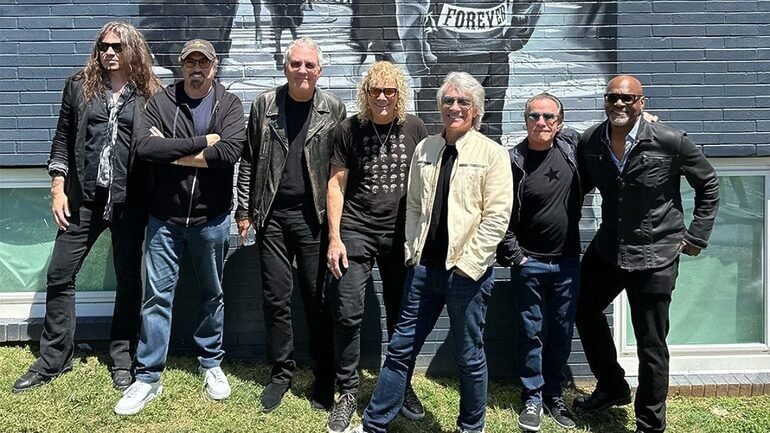 Banda Bon Jovi completa em frente a um mural